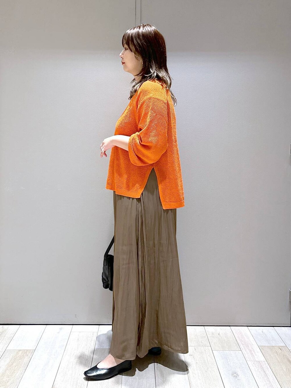 ブラック系のショルダーバッグ、オレンジ系のニット/セーター、ブラウン系のその他パンツを着用したレディースの秋コーディネートの4枚目の写真