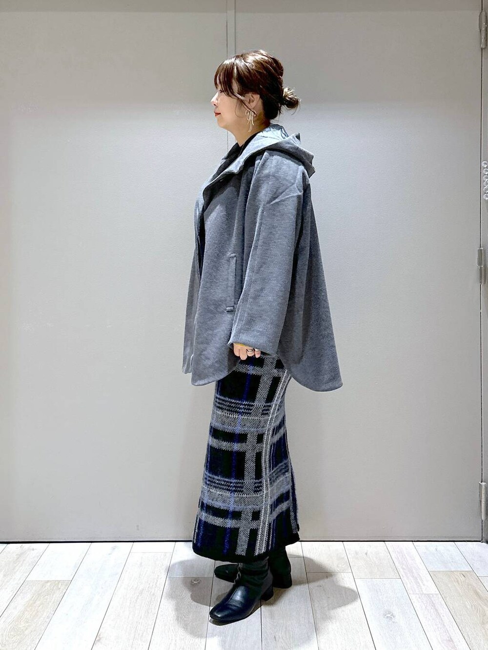 シルバー系のショルダーバッグ、グレー系のポンチョ、ブラック系のニット/セーターを着用したレディースの秋コーディネートの4枚目の写真