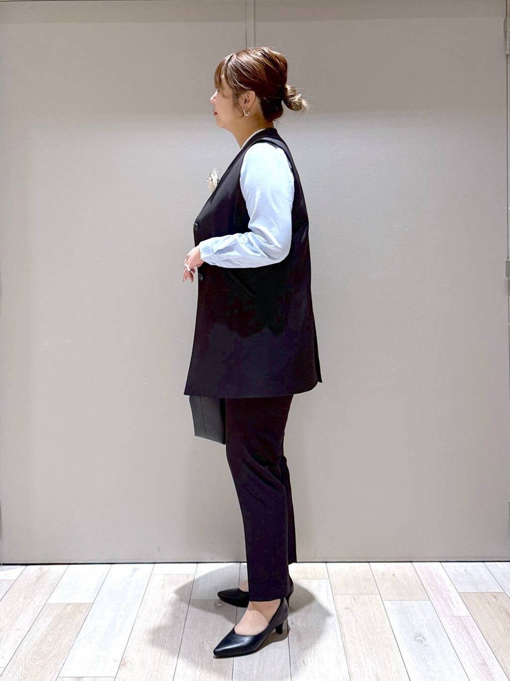 ブラック系のスーツパンツ、ブラック系のスーツベスト、ブルー系のシャツ/ブラウスを着用したレディースの冬コーディネートの4枚目の写真