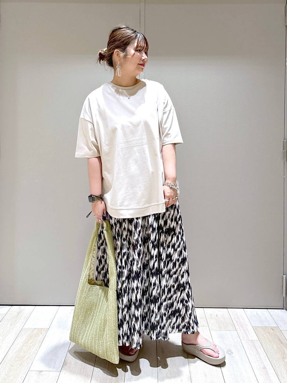 ゴールド系のショルダーバッグ、ブラック系のスカート、ベージュ系のTシャツ/カットソーを着用したレディースの春コーディネートの5枚目の写真