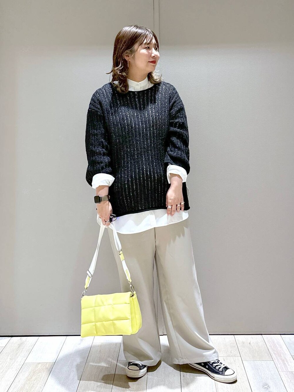 イエロー系のショルダーバッグ、ブラック系のTシャツ/カットソー、ベージュ系のスラックスを着用したレディースの春コーディネートの5枚目の写真