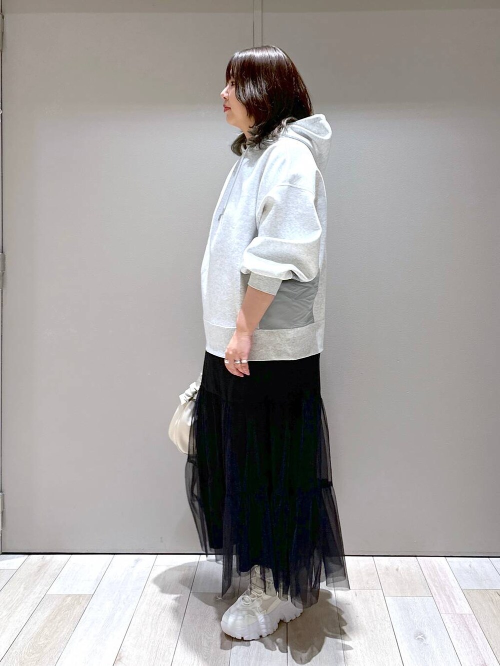 ホワイト系のスニーカー、グレー系のパーカー、ホワイト系のショルダーバッグを着用したレディースの冬コーディネートの4枚目の写真