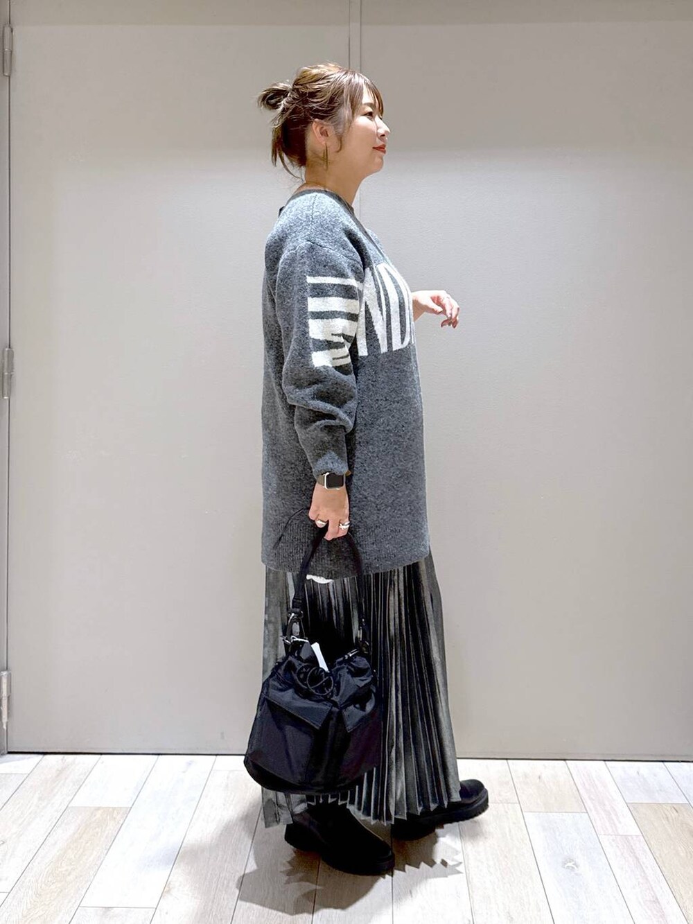 ブラック系のショルダーバッグ、ブラック系のブーツ、グレー系のスカートを着用したレディースの冬コーディネートの2枚目の写真