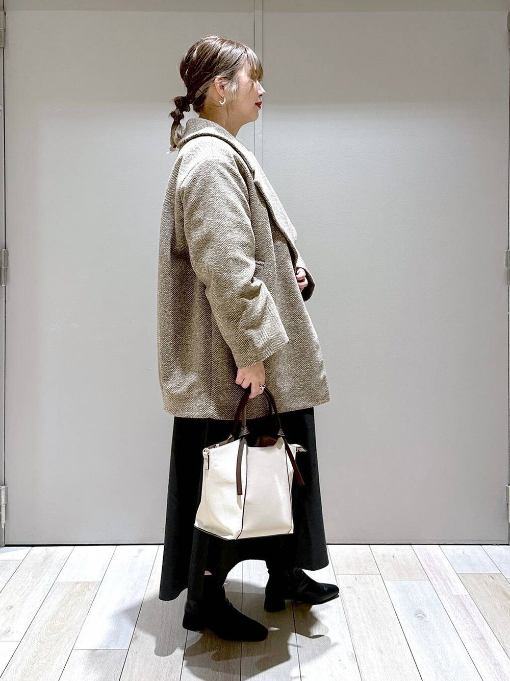 ブラウン系のチェスターコート、ベージュ系のショルダーバッグ、ブラック系のブーツを着用したレディースの秋コーディネートの2枚目の写真