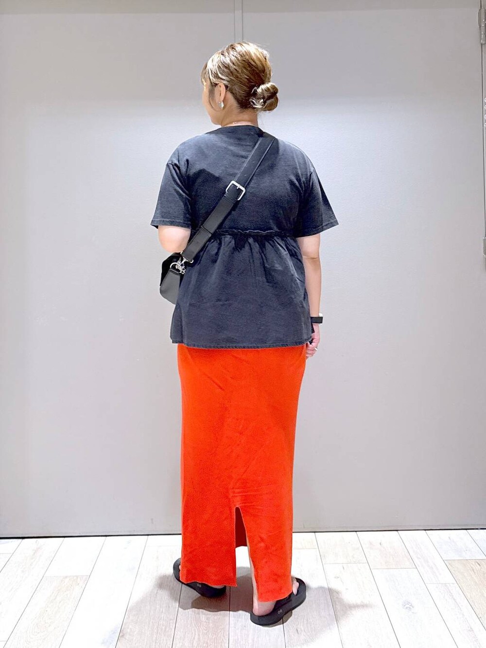 オレンジ系のスカート、ブラック系のTシャツ/カットソー、ブラック系のショルダーバッグを着用したレディースの夏コーディネートの3枚目の写真