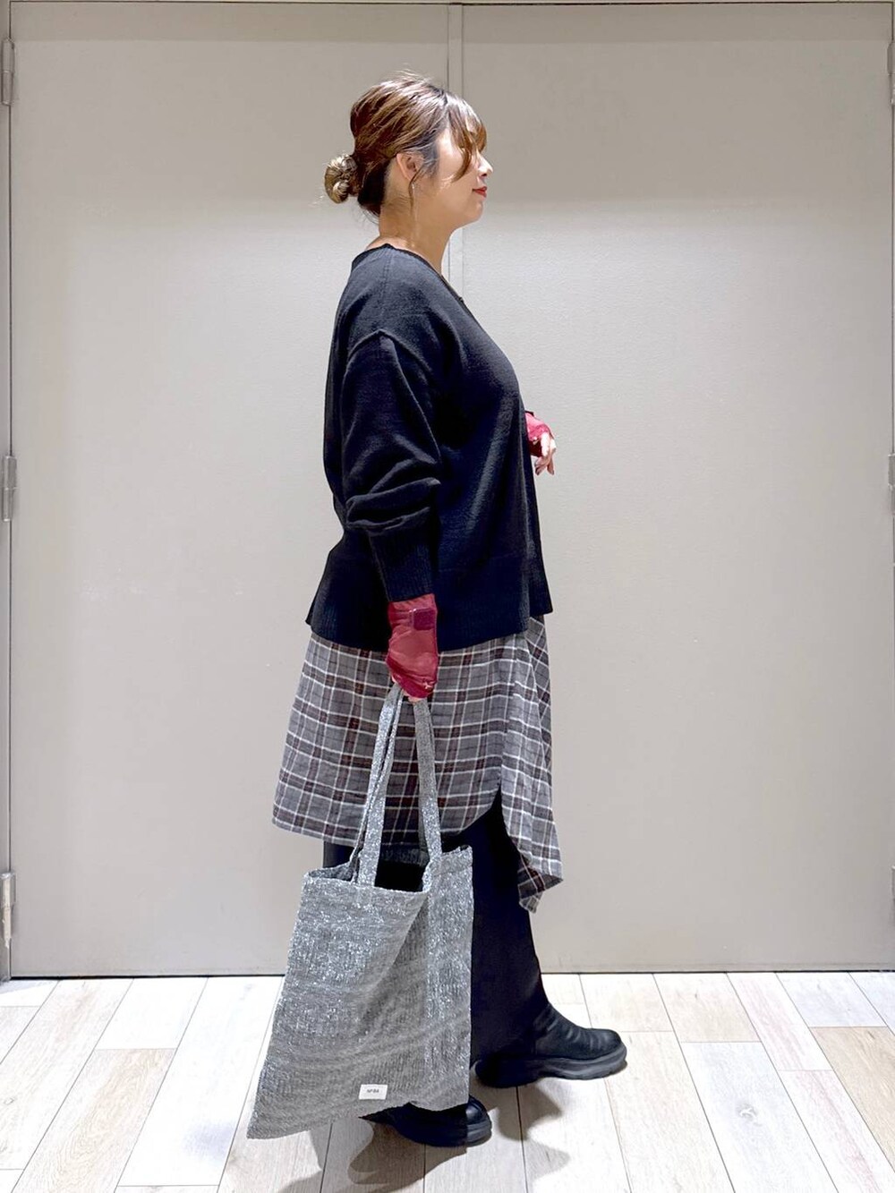 シルバー系のトートバッグ、ブラック系のニット/セーター、ブラック系のスカートを着用したレディースの冬コーディネートの2枚目の写真