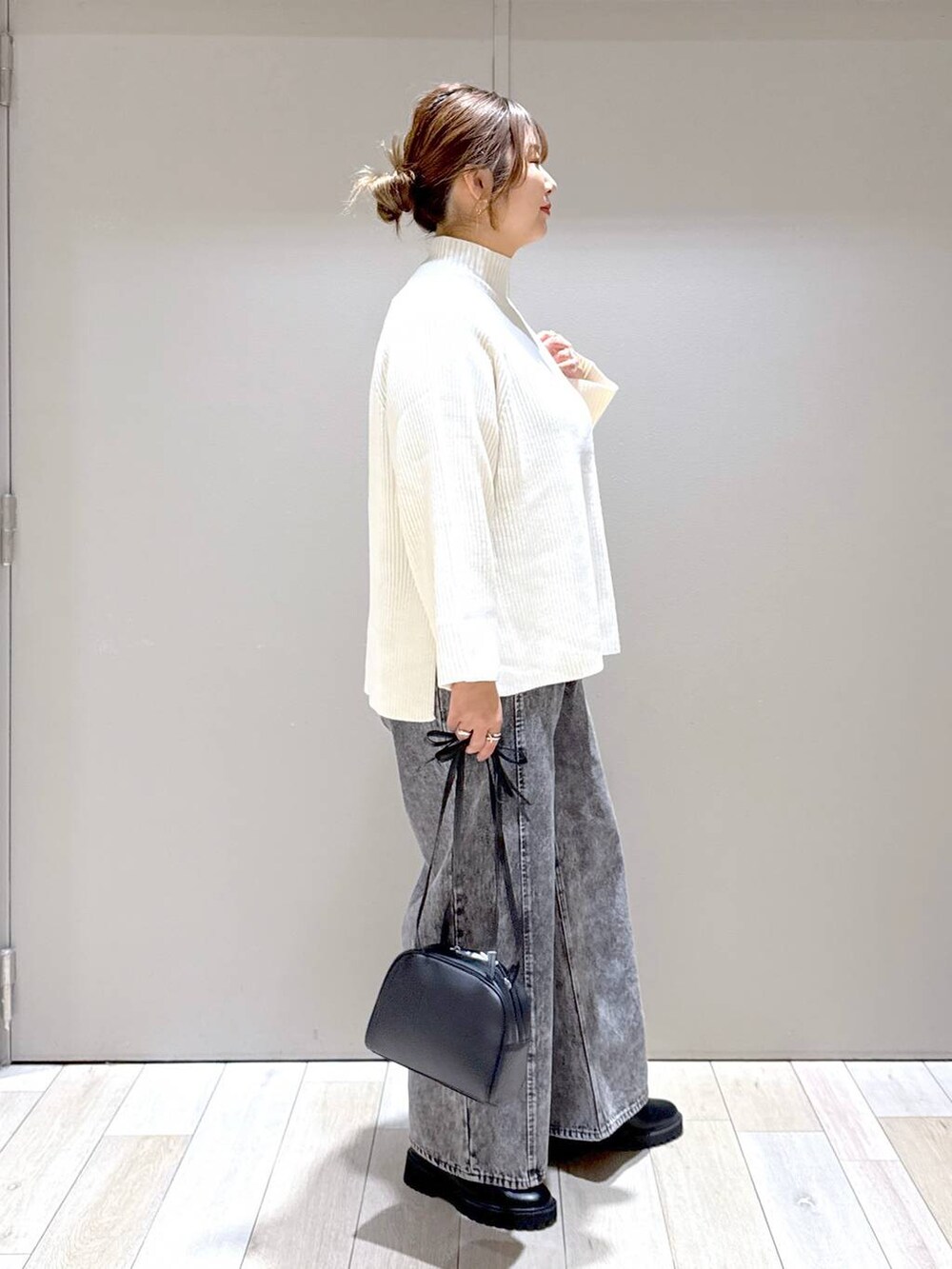 ブラック系のブーツ、ホワイト系のニット/セーター、グレー系のデニムパンツを着用したレディースの冬コーディネートの3枚目の写真