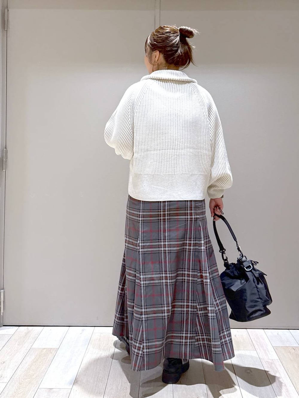 ブラック系のショルダーバッグ、ホワイト系のカーディガン/ボレロ、ブラック系のブーツを着用したレディースの冬コーディネートの3枚目の写真