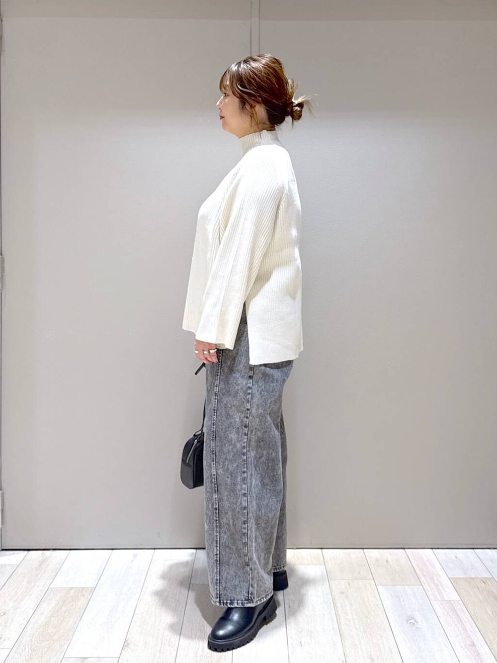 ブラック系のブーツ、ホワイト系のニット/セーター、グレー系のデニムパンツを着用したレディースの冬コーディネートの4枚目の写真