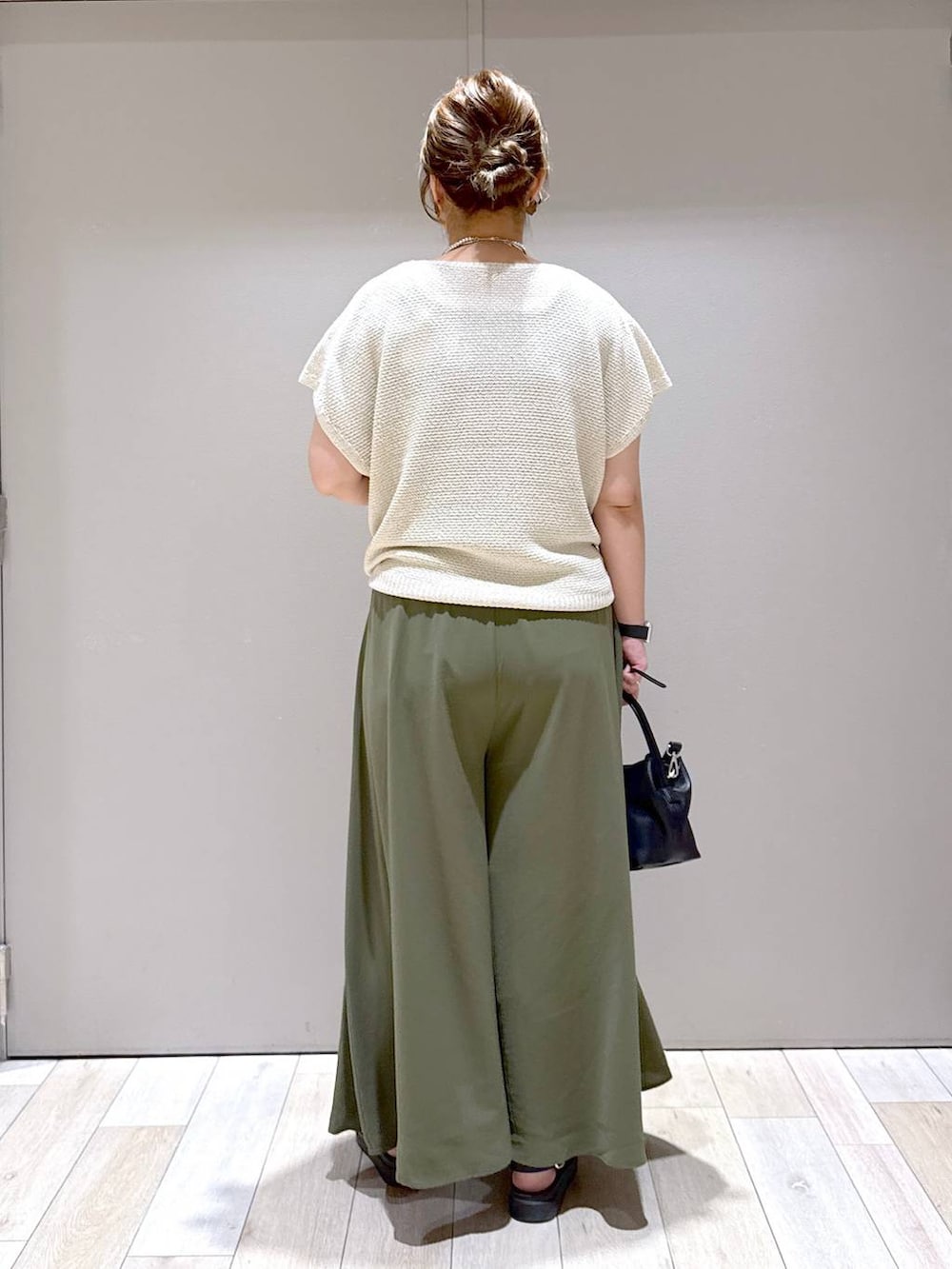 グリーン系のその他パンツ、ホワイト系のニット/セーター、ブラック系のサンダルを着用したレディースの夏コーディネートの3枚目の写真