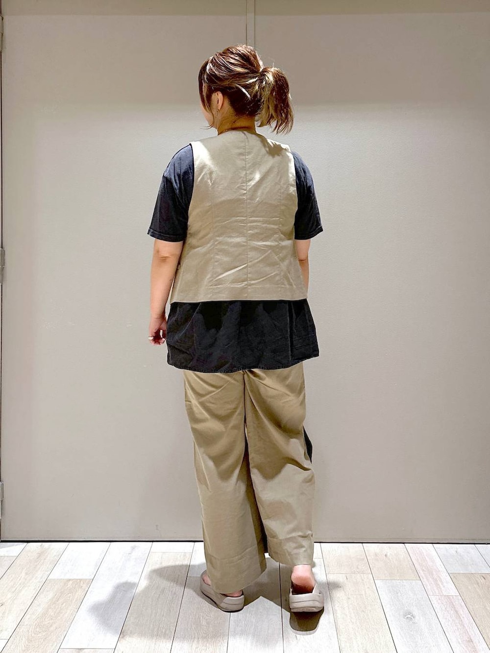 ブラック系のショルダーバッグ、ブラウン系のベスト、ベージュ系のサンダルを着用したレディースの夏コーディネートの3枚目の写真