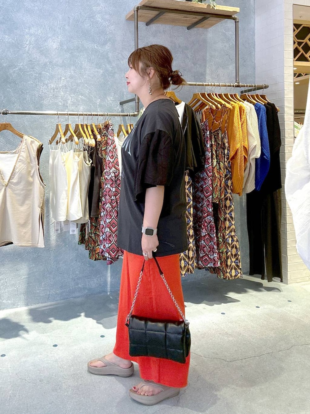 ブラック系のショルダーバッグ、レッド系のスカート、ベージュ系のサンダルを着用したレディースの夏コーディネートの2枚目の写真