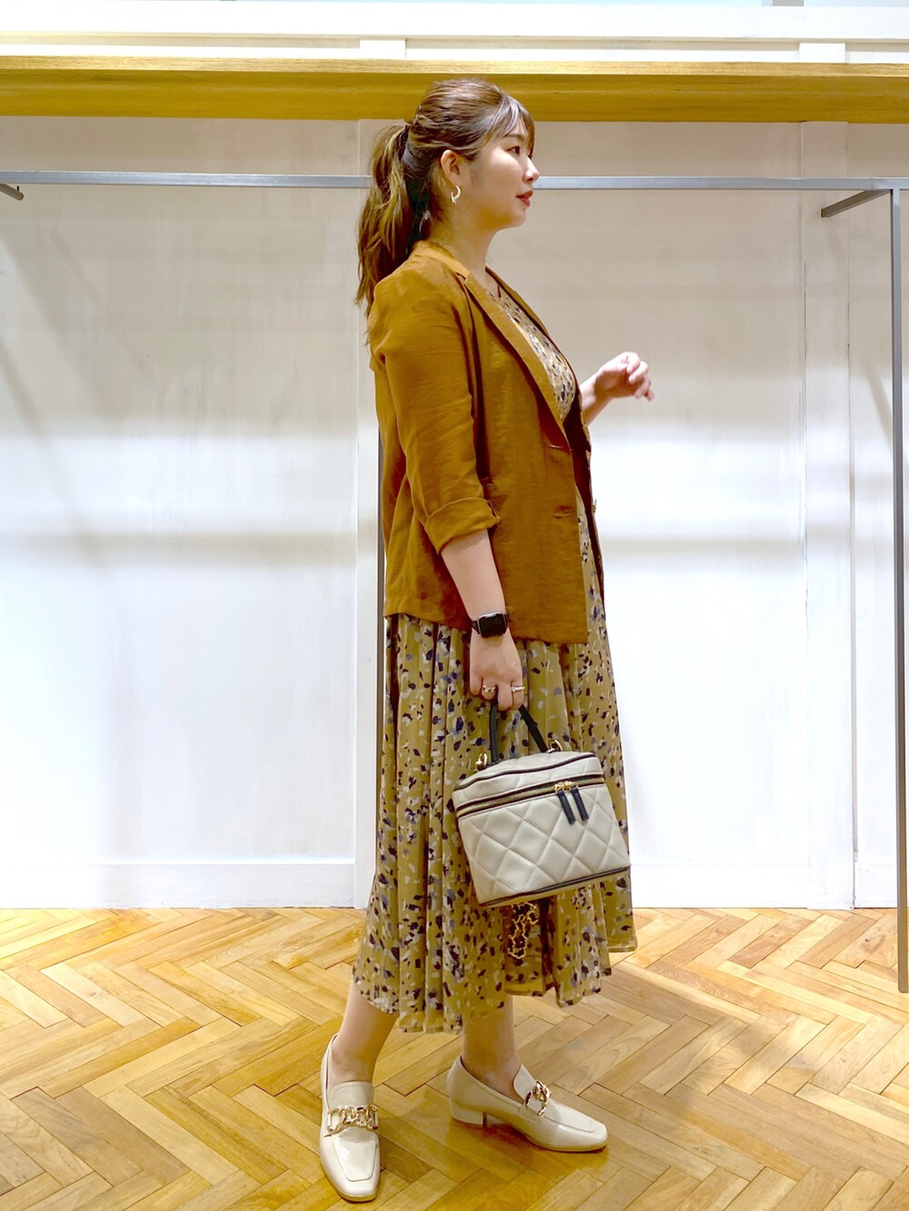 ブラウン系のテーラードジャケット、イエロー系のワンピース、ベージュ系のショルダーバッグを着用したレディースの夏コーディネートの2枚目の写真