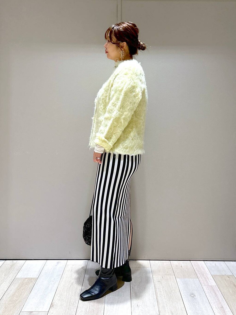 ブラック系のショルダーバッグ、ブラック系のスカート、グリーン系のカーディガン/ボレロを着用したレディースの秋コーディネートの4枚目の写真