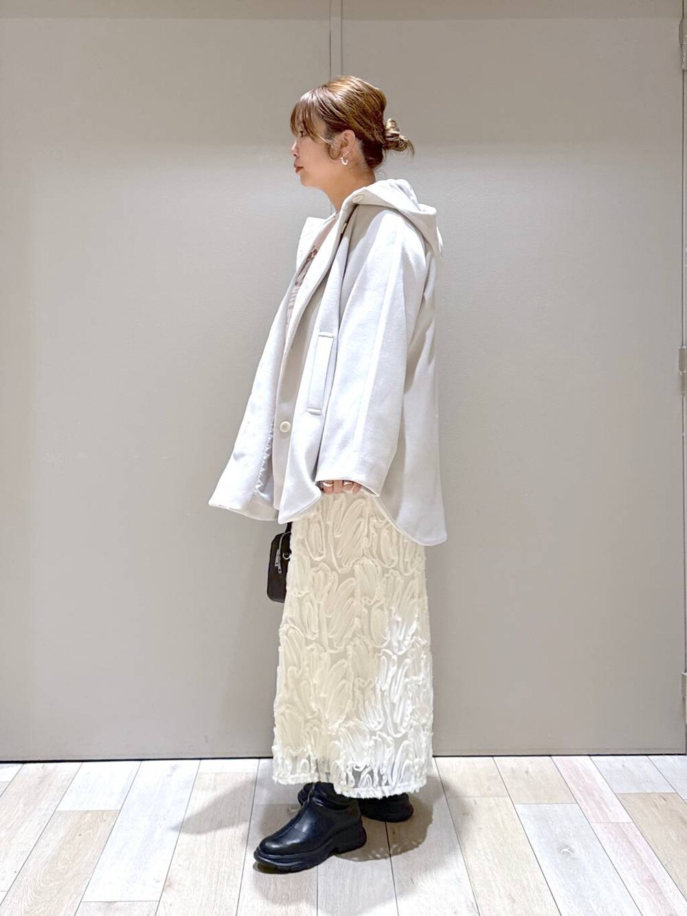 ホワイト系のポンチョ、ブラック系のブーツ、ピンク系のスウェットを着用したレディースの冬コーディネートの3枚目の写真