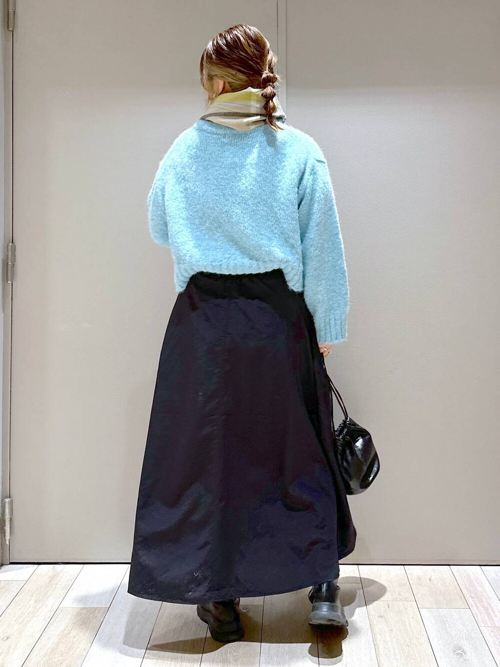 ブラック系のショルダーバッグ、ブラック系のブーツ、ブラック系のスカートを着用したレディースの冬コーディネートの5枚目の写真