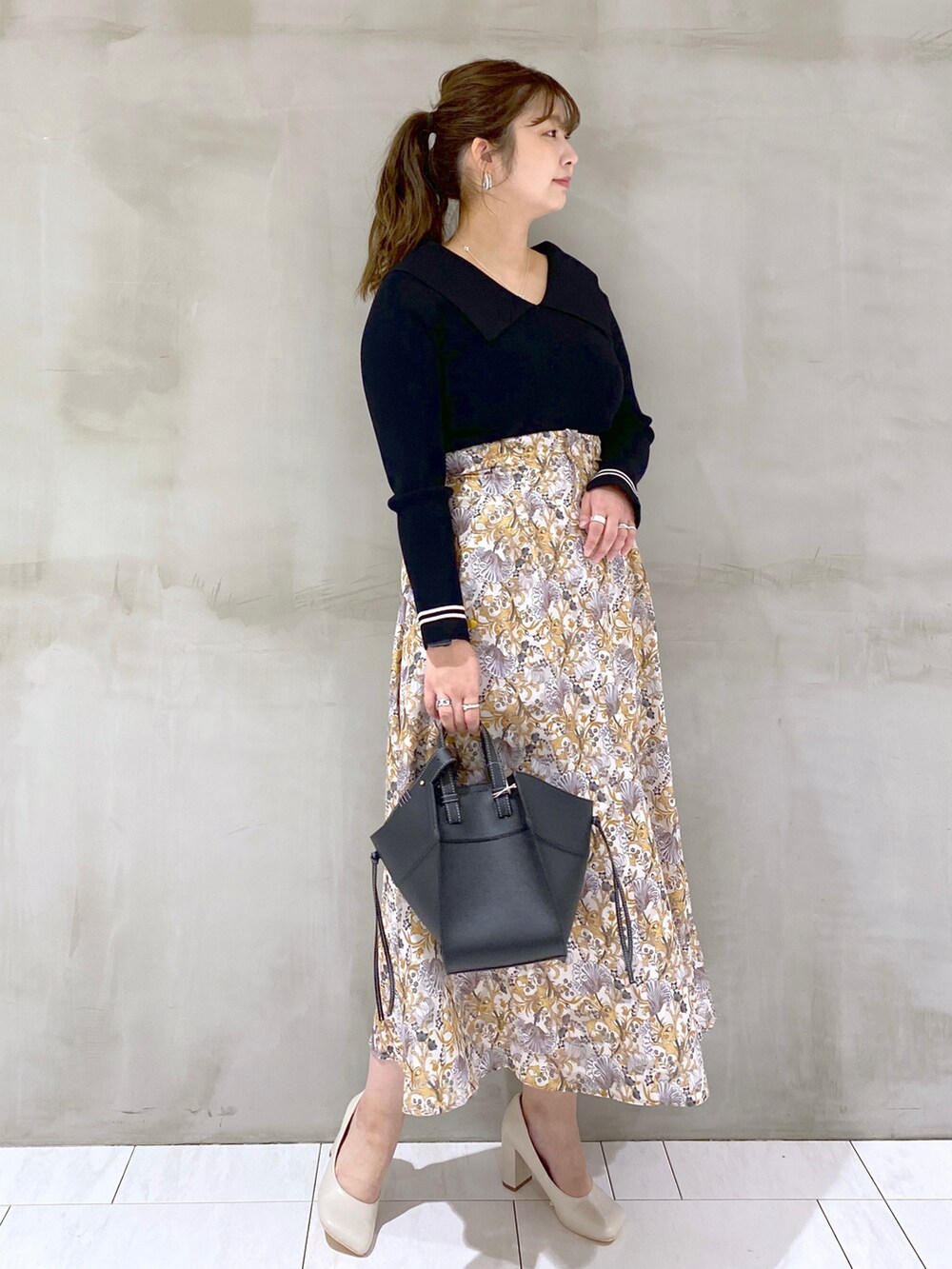 ブラック系のニット/セーター、ホワイト系のスカート、ブラック系のショルダーバッグを着用したレディースの春コーディネートの3枚目の写真