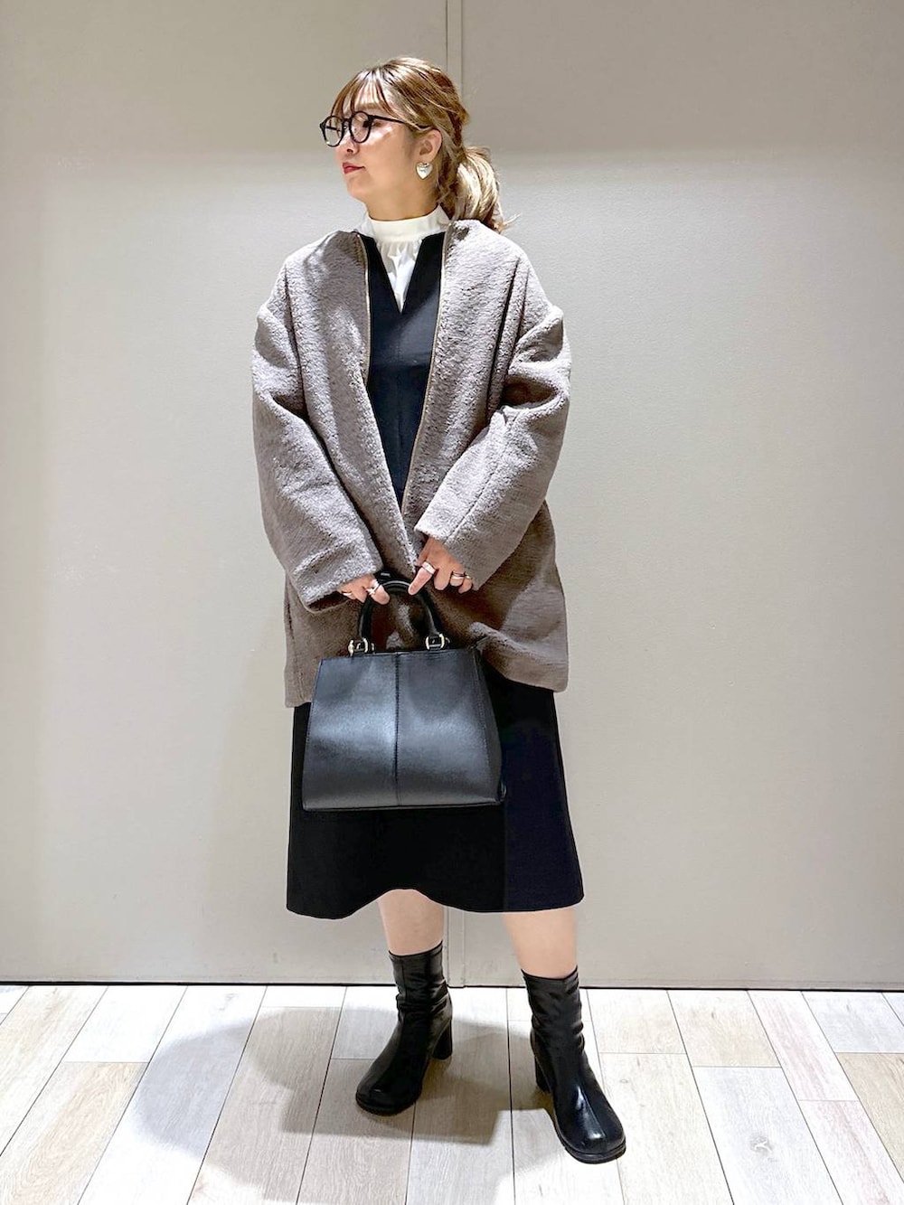 ブラウン系のノーカラーコート、ブラック系のブーツ、ホワイト系のシャツ/ブラウスを着用したレディースの冬コーディネートの6枚目の写真
