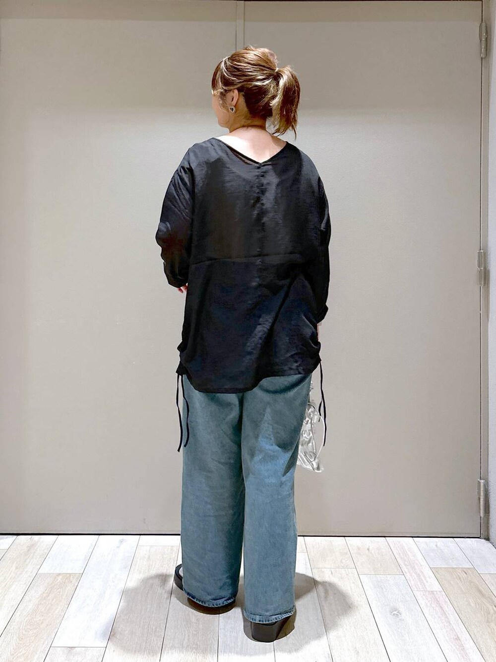 シルバー系のショルダーバッグ、ブルー系のデニムパンツ、シルバー系のサンダルを着用したレディースの秋コーディネートの3枚目の写真