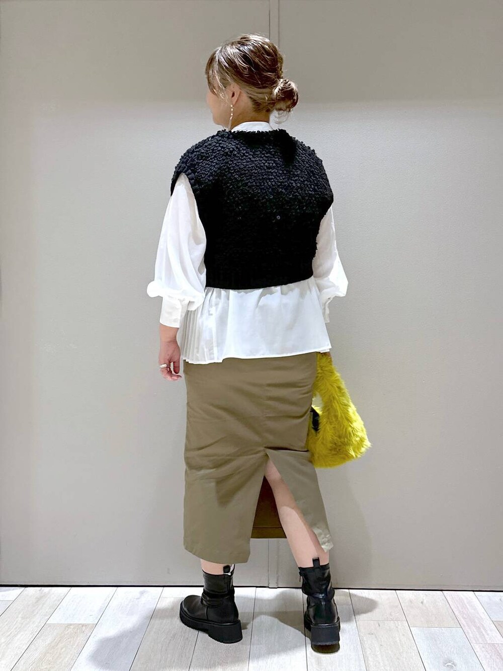 イエロー系のハンドバッグ、ブラック系のブーツ、ホワイト系のシャツ/ブラウスを着用したレディースの秋コーディネートの3枚目の写真