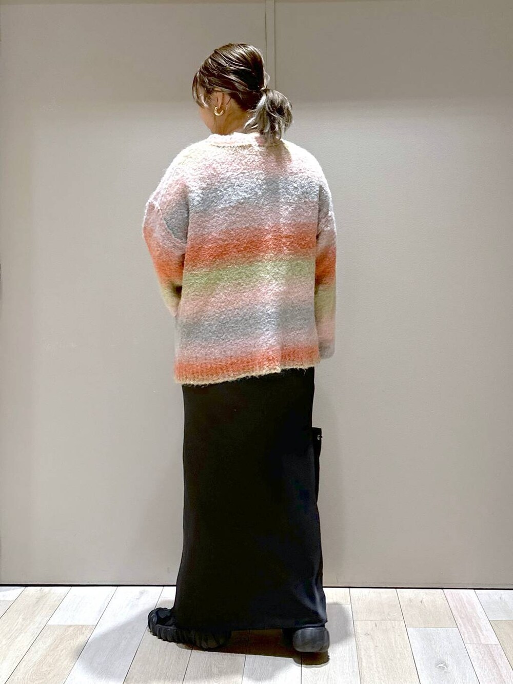 ブラック系のスカート、オレンジ系のニット/セーターを着用したレディースの秋コーディネートの3枚目の写真