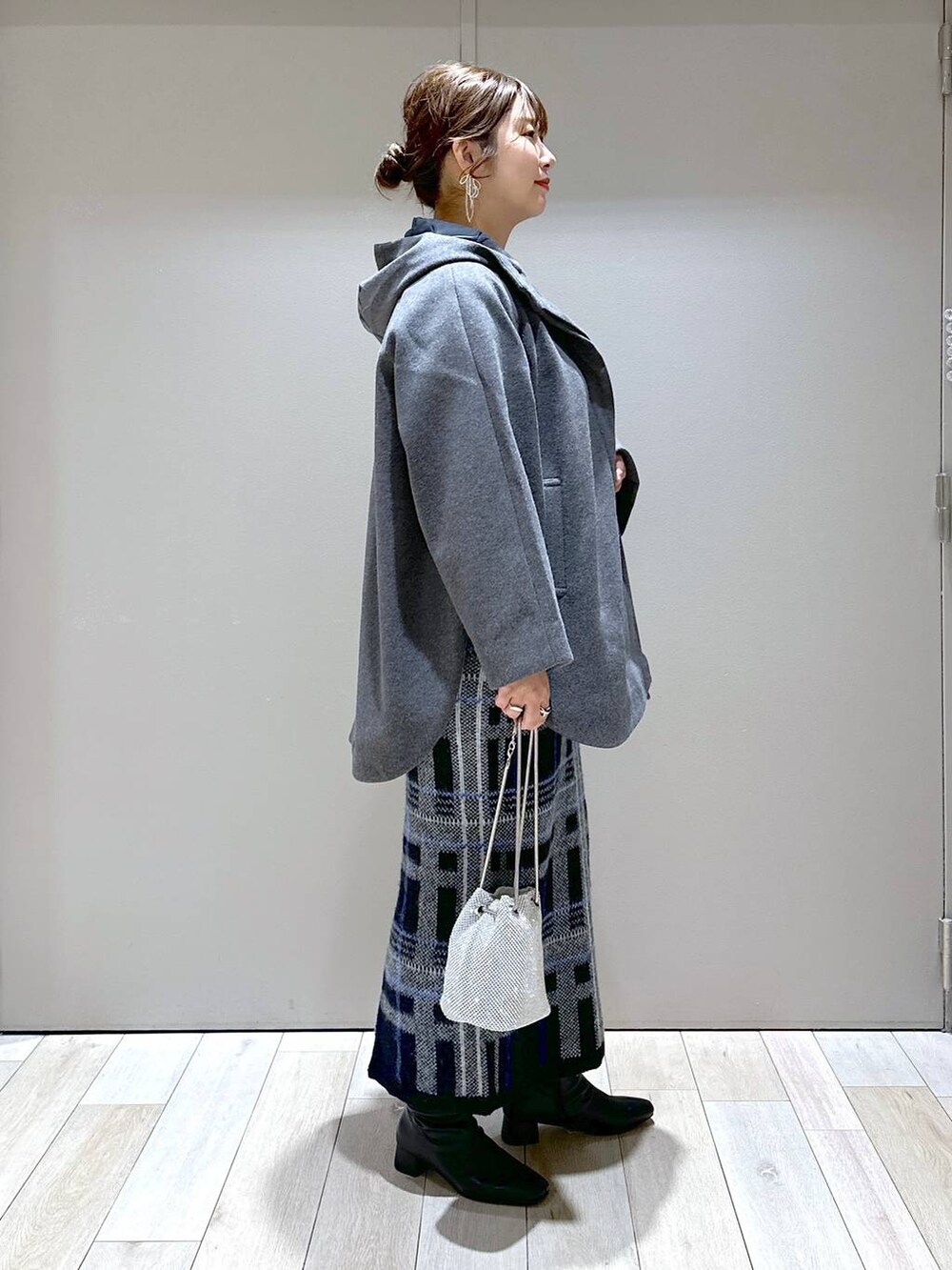 シルバー系のショルダーバッグ、グレー系のポンチョ、ブラック系のニット/セーターを着用したレディースの秋コーディネートの2枚目の写真