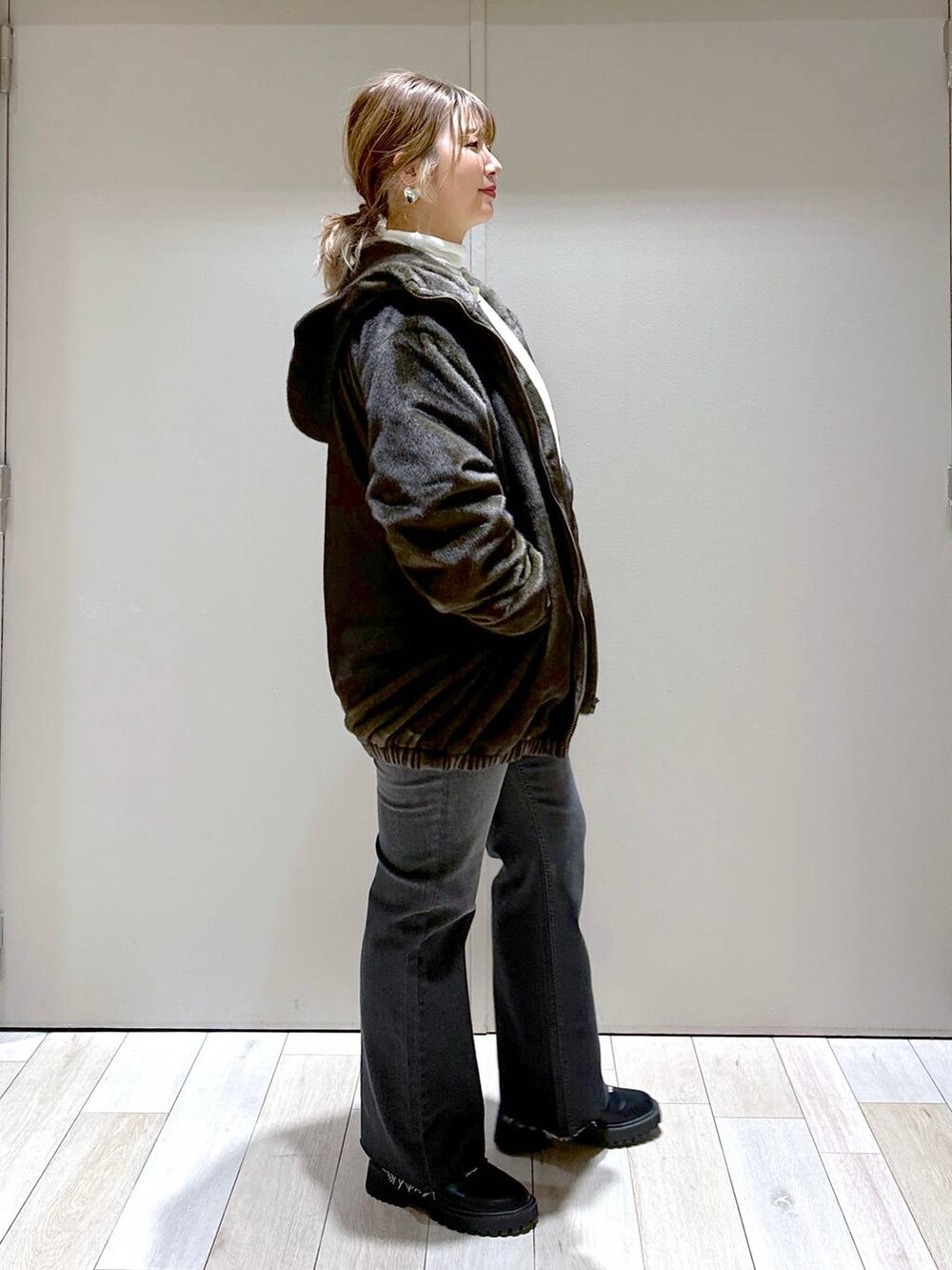 ホワイト系のTシャツ/カットソー、グリーン系のブルゾン、ブラック系のブーツを着用したレディースの冬コーディネートの2枚目の写真