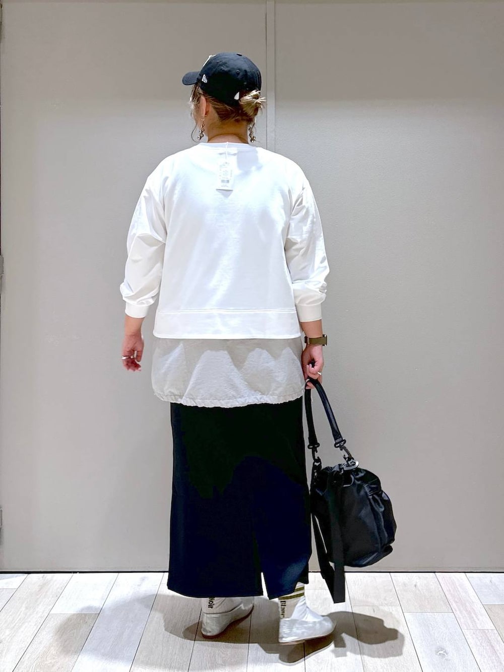 ブラック系のスカート、グレー系のパンプス、ブラック系のショルダーバッグを着用したレディースの春コーディネートの3枚目の写真