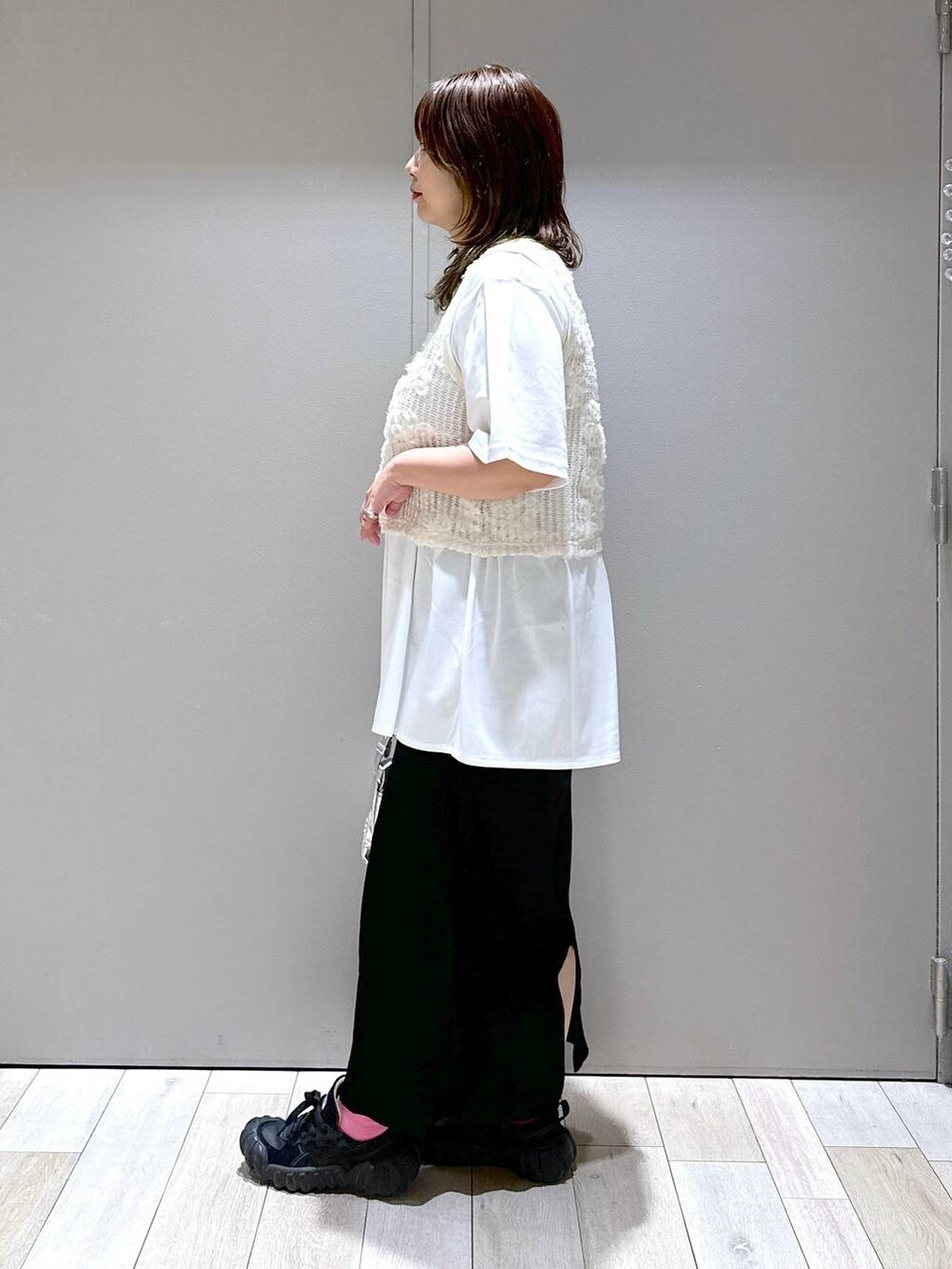 シルバー系のショルダーバッグ、ホワイト系のTシャツ/カットソー、ブラック系のスカートを着用したレディースの秋コーディネートの4枚目の写真