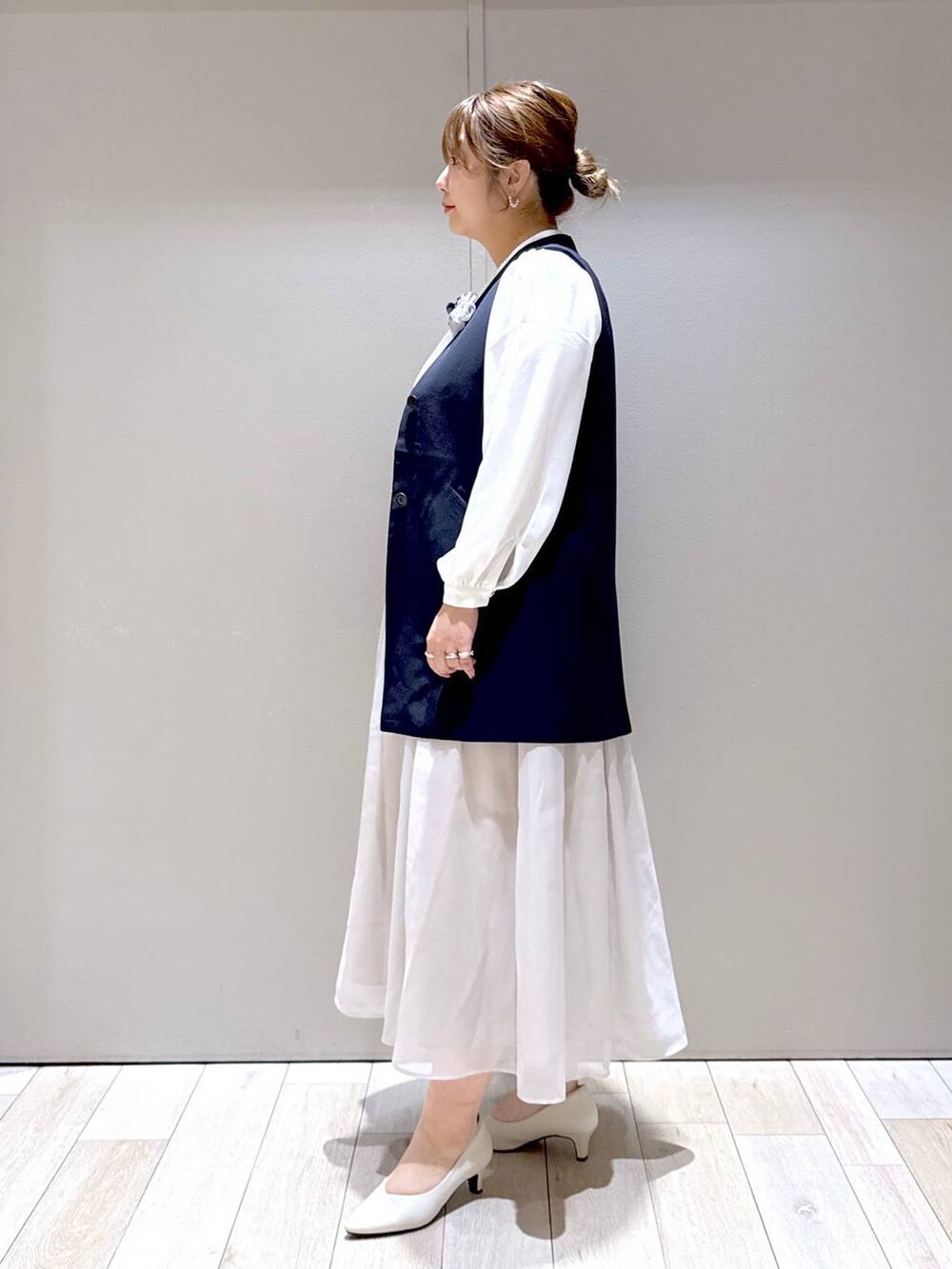 ベージュ系のスカート、ホワイト系のシャツ/ブラウス、ブルー系のスーツベストを着用したレディースの冬コーディネートの3枚目の写真