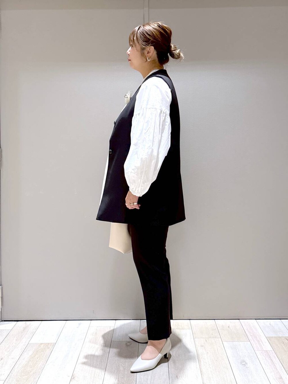 ブラック系のスーツパンツ、ブラック系のスーツベスト、ホワイト系のパンプスを着用したレディースの冬コーディネートの4枚目の写真