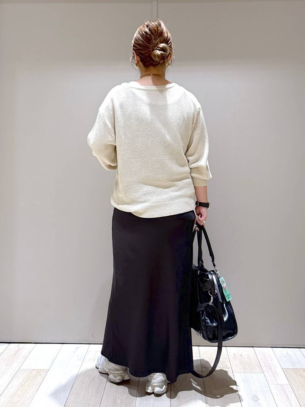 ブラック系のスカート、ブラック系のトートバッグ、ホワイト系のニット/セーターを着用したレディースの春コーディネートの3枚目の写真