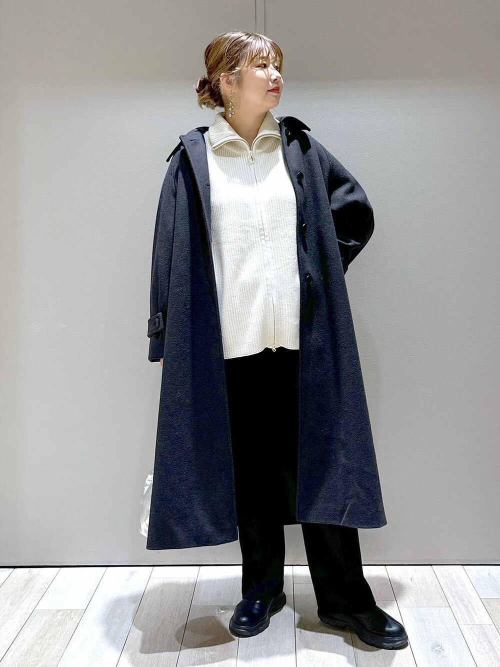 ブラック系のその他パンツ、グレー系のステンカラーコート、ホワイト系のニット/セーターを着用したレディースの冬コーディネートの5枚目の写真