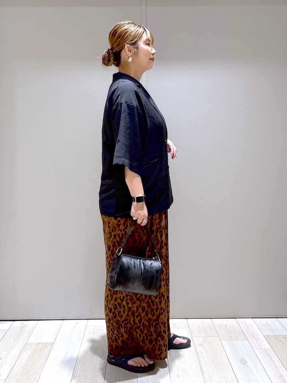 ブラック系のテーラードジャケット、ブラック系のサンダル、ブラック系のハンドバッグを着用したレディースの夏コーディネートの2枚目の写真