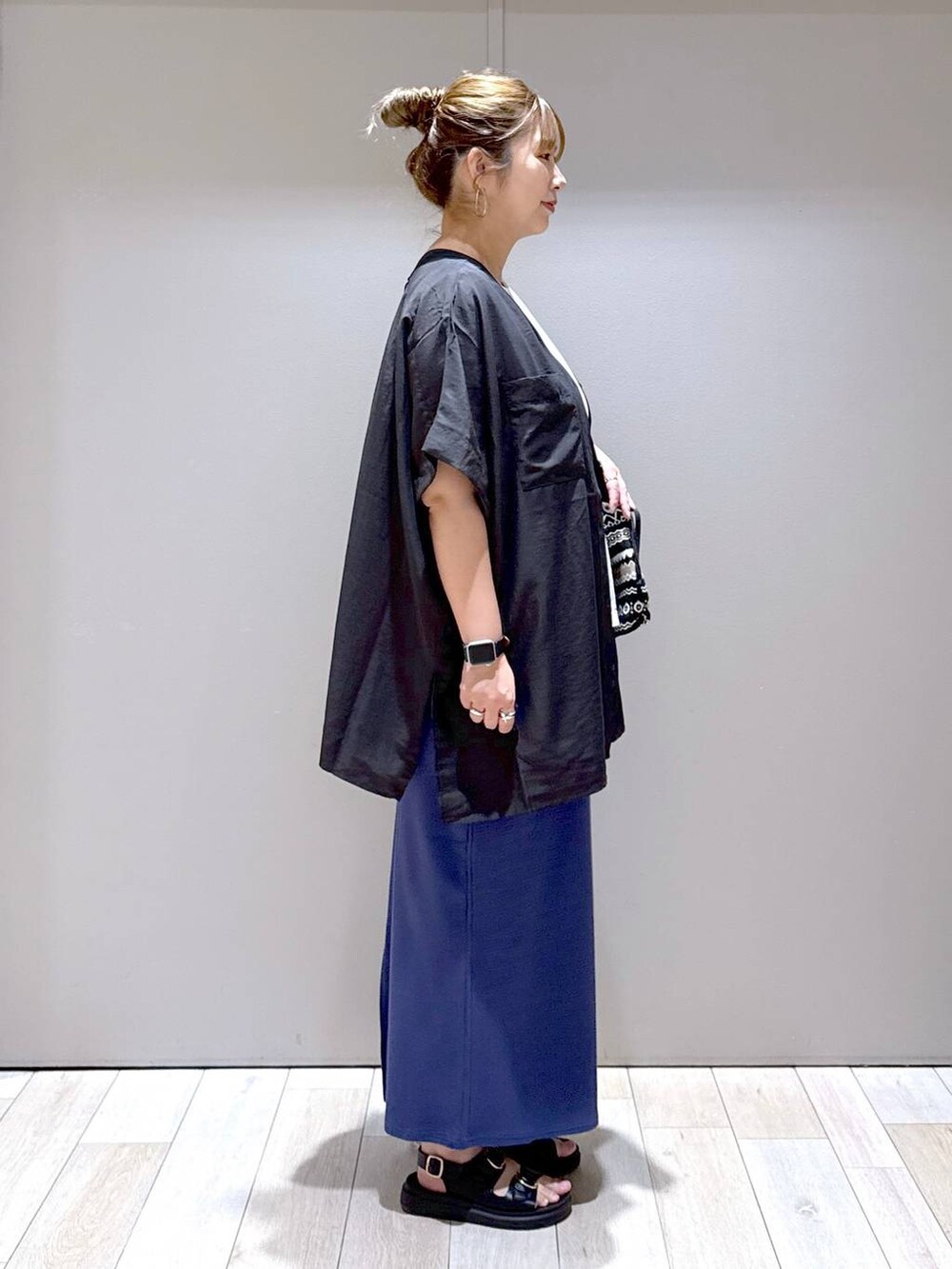 ブルー系のスカート、ブラック系のサンダル、ホワイト系のTシャツ/カットソーを着用したレディースの夏コーディネートの2枚目の写真