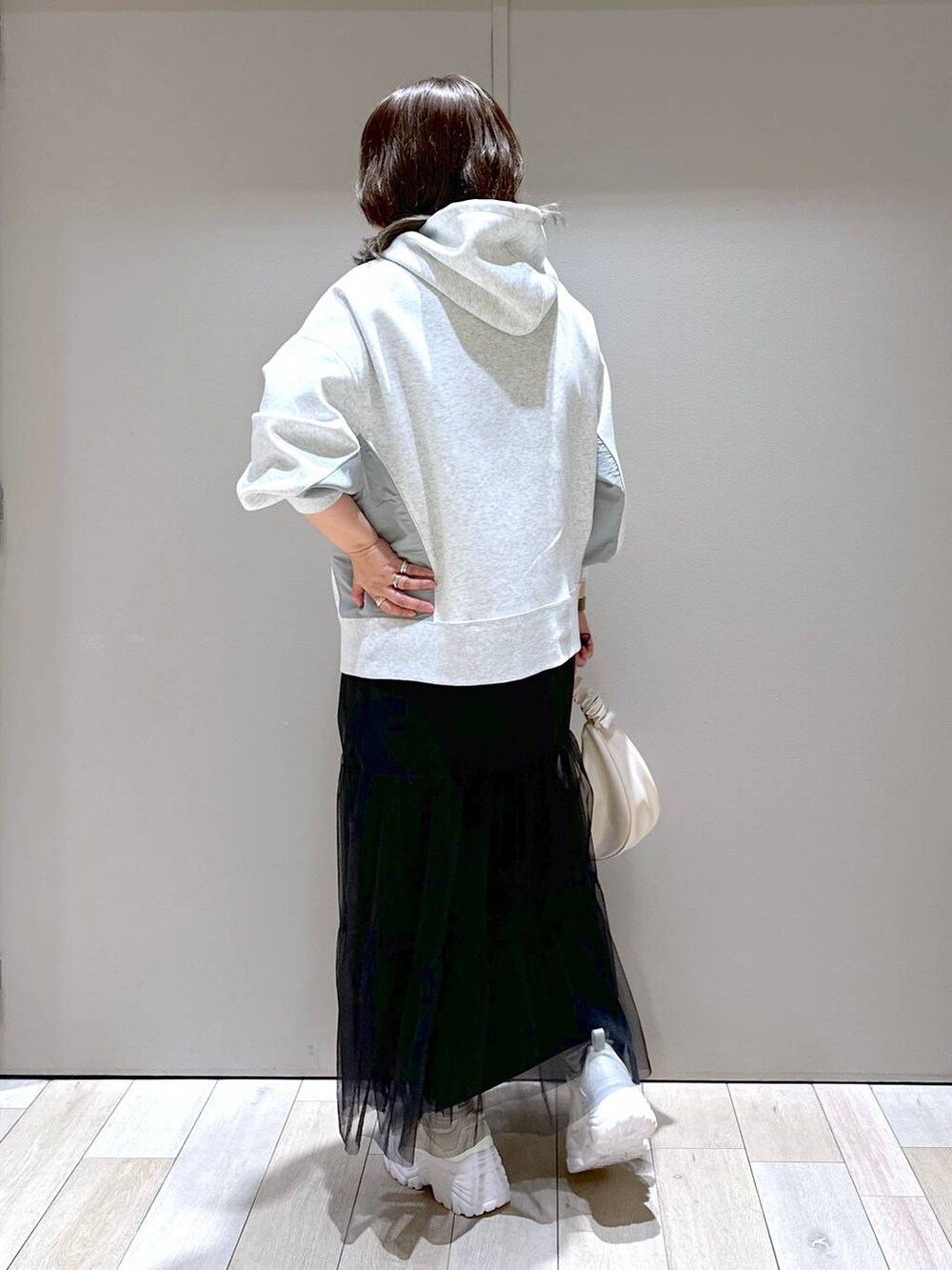 ホワイト系のスニーカー、グレー系のパーカー、ホワイト系のショルダーバッグを着用したレディースの冬コーディネートの3枚目の写真