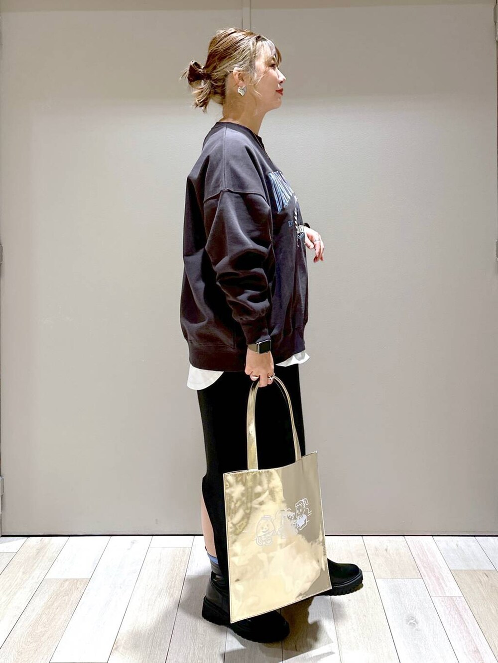 ブラック系のスカート、グレー系のスウェット、ブラック系のブーツを着用したレディースの冬コーディネートの2枚目の写真