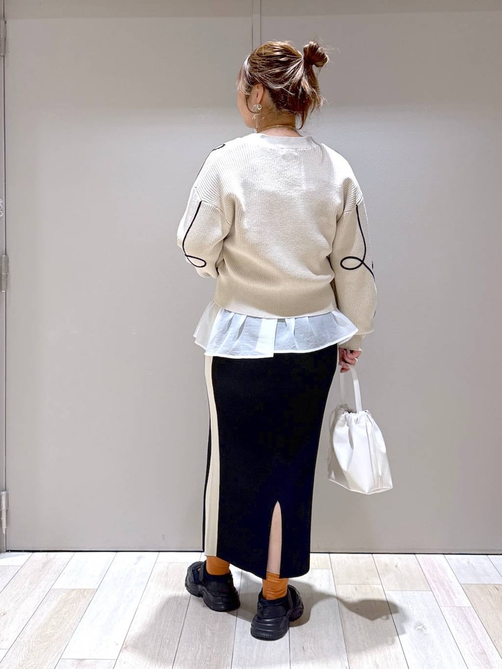 ホワイト系のTシャツ/カットソー、ブラック系のスニーカー、ブラック系のスカートを着用したレディースの春コーディネートの3枚目の写真