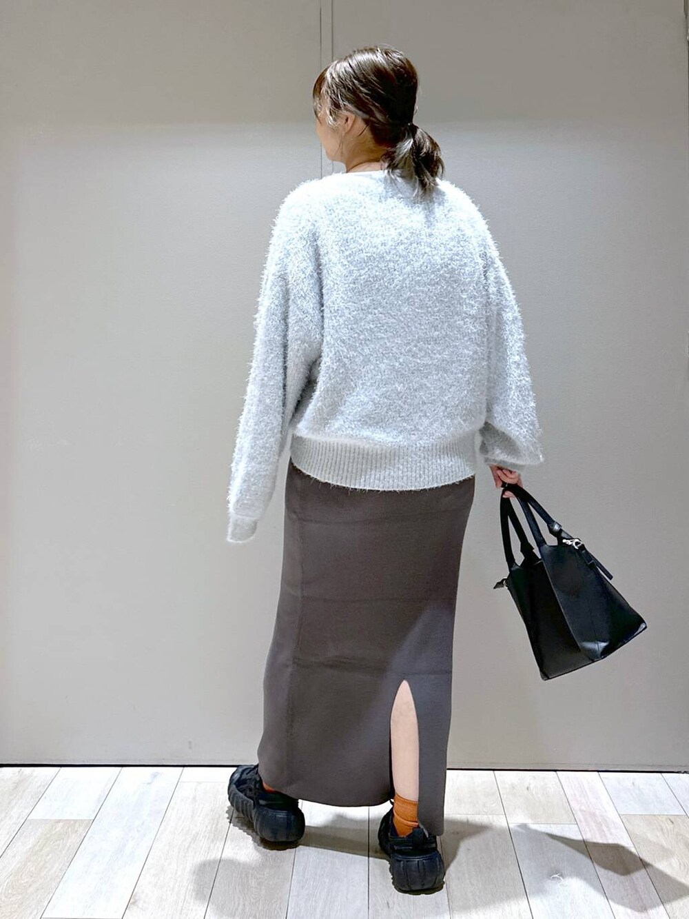 グレー系のスカート、ホワイト系のTシャツ/カットソー、ブラック系のショルダーバッグを着用したレディースの秋コーディネートの3枚目の写真