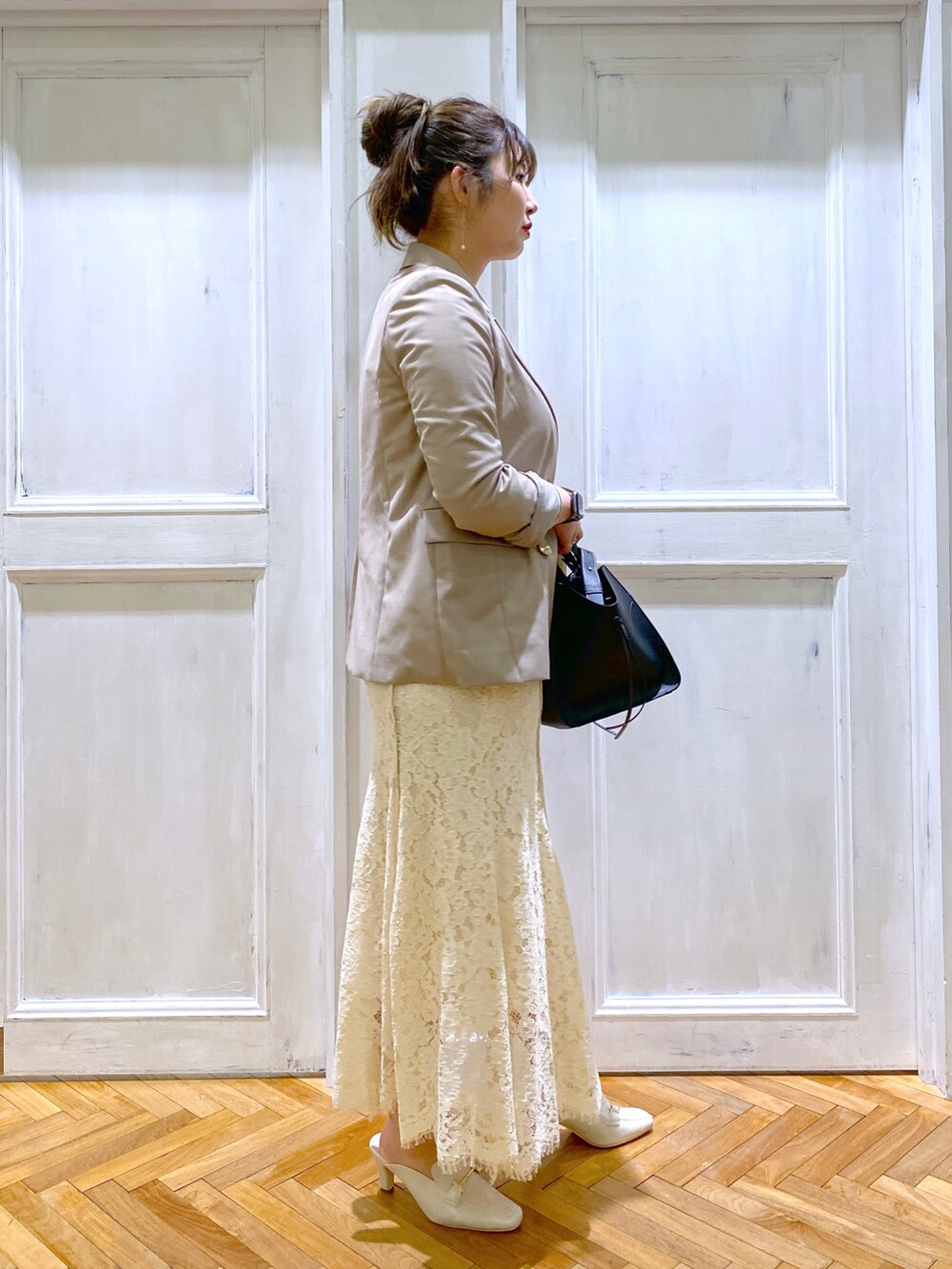 ベージュ系のテーラードジャケット、ホワイト系のスカート、ホワイト系のサンダルを着用したレディースの春コーディネートの2枚目の写真