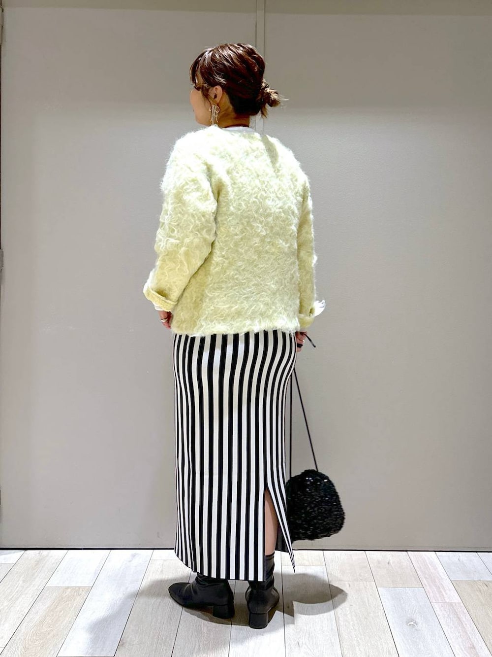 ブラック系のショルダーバッグ、ブラック系のスカート、グリーン系のカーディガン/ボレロを着用したレディースの秋コーディネートの3枚目の写真