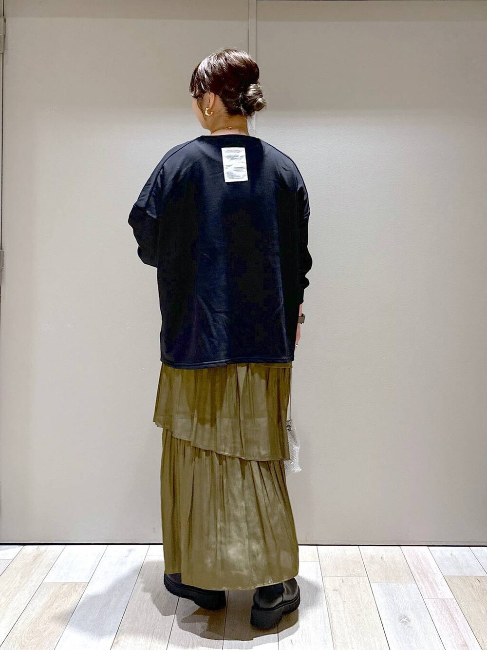 シルバー系のショルダーバッグ、ブラック系のブーツ、グリーン系のスカートを着用したレディースの秋コーディネートの3枚目の写真