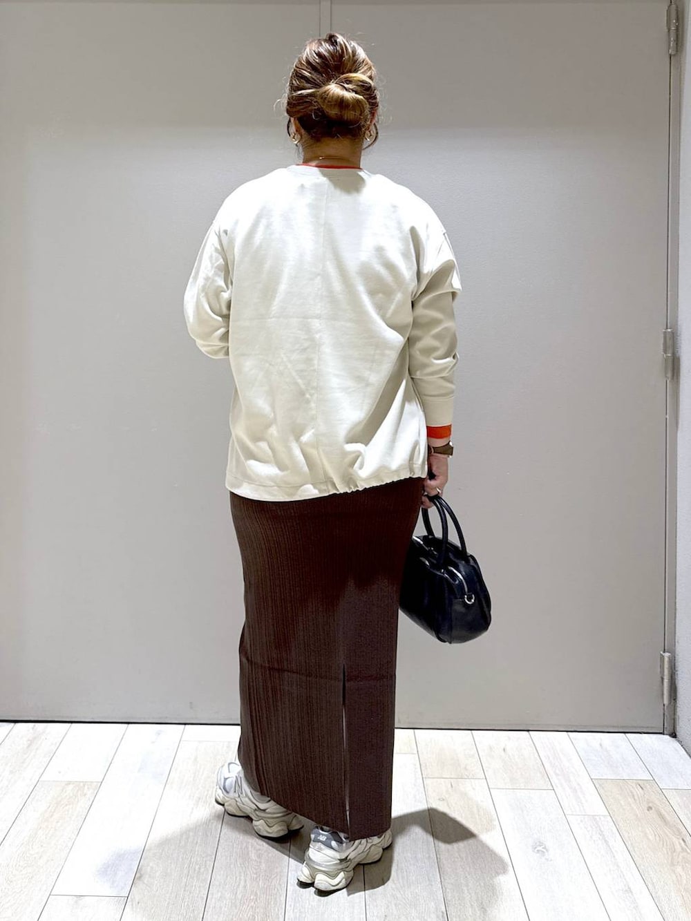 ブラック系のショルダーバッグ、ベージュ系のTシャツ/カットソー、ブラウン系のスカートを着用したレディースの秋コーディネートの3枚目の写真