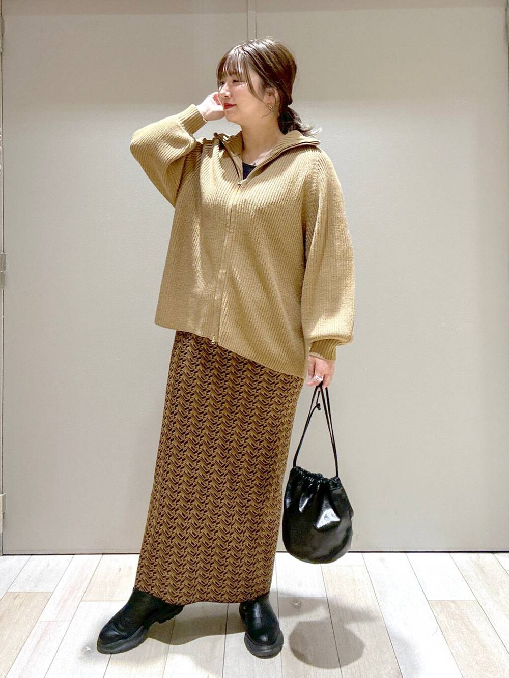 ブラウン系のスカート、ブラウン系のニット/セーター、ブラック系のブーツを着用したレディースの冬コーディネートの4枚目の写真