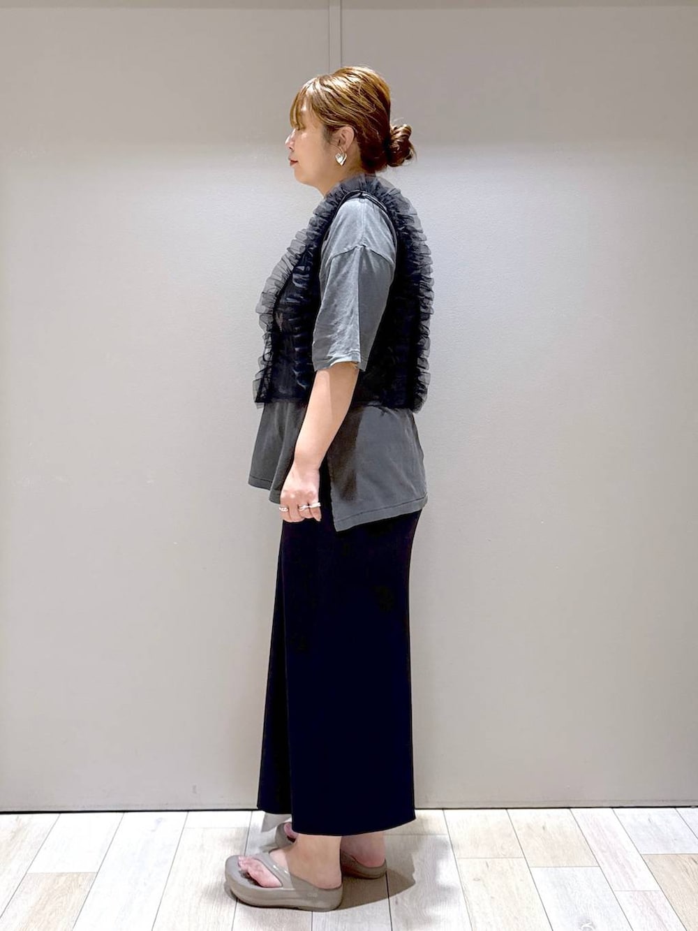 オレンジ系のトートバッグ、ブラック系のベスト、ベージュ系のサンダルを着用したレディースの夏コーディネートの4枚目の写真