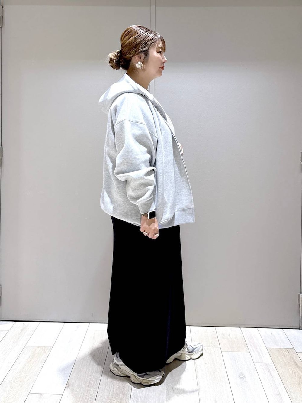 グレー系のパーカー、ブラック系のスカート、ホワイト系のマタニティウェア/グッズを着用したレディースの秋コーディネートの2枚目の写真