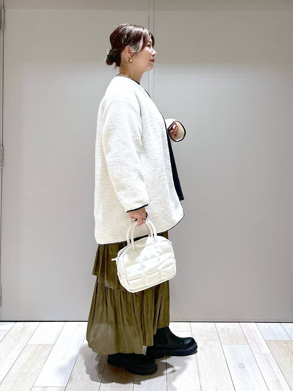 ホワイト系のボストンバッグ、ホワイト系のその他アウター、ブラック系のブーツを着用したレディースの秋コーディネートの2枚目の写真