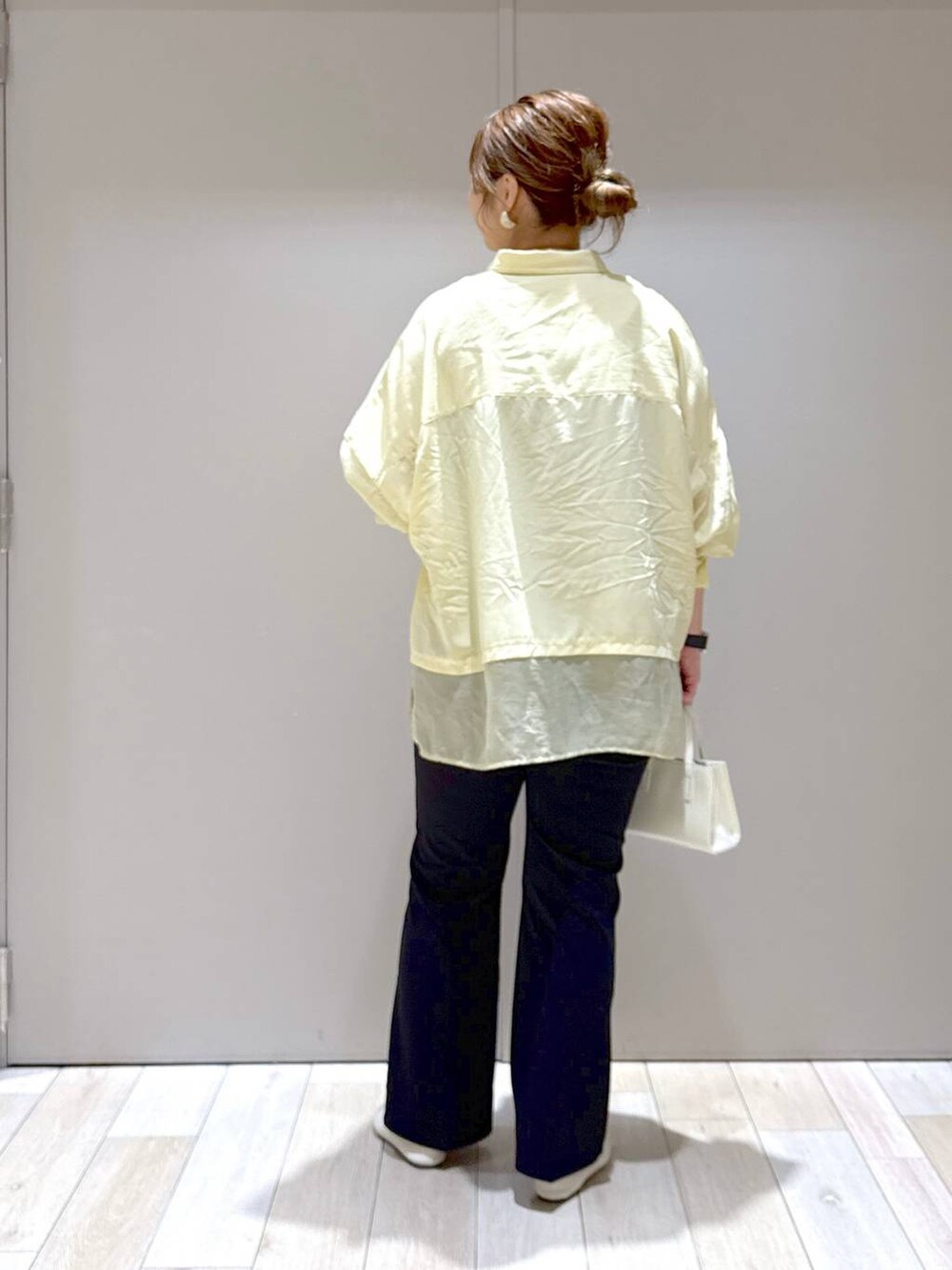 ブラック系のスラックス、ホワイト系のパンプス、イエロー系のシャツ/ブラウスを着用したレディースの春コーディネートの3枚目の写真