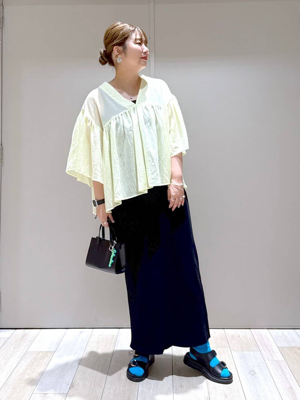 ブラック系のスカート、イエロー系のシャツ/ブラウス、ブラック系のサンダルを着用したレディースの夏コーディネートの5枚目の写真