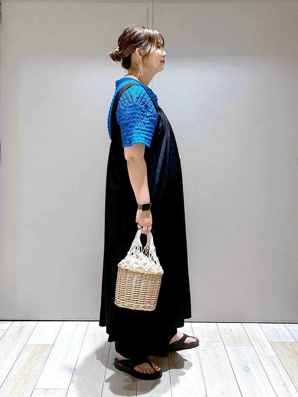 ホワイト系のかごバッグ、ブラック系のサンダル、ブラック系のスラックスを着用したレディースの夏コーディネートの2枚目の写真